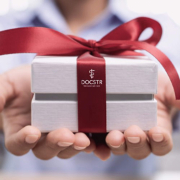 Geschenk mit roter Schleife und DOCSTR Logo