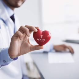 Arzt zeigt rotes Herz mit DOCSTR Logo